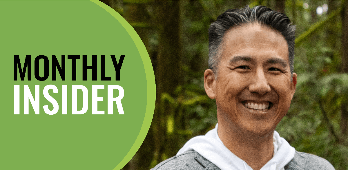 A man smiling in front of a forest with the words 