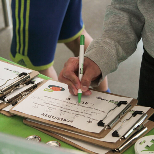 A student fills out a survey on a clipboard at a Plant Powered Popups event.
